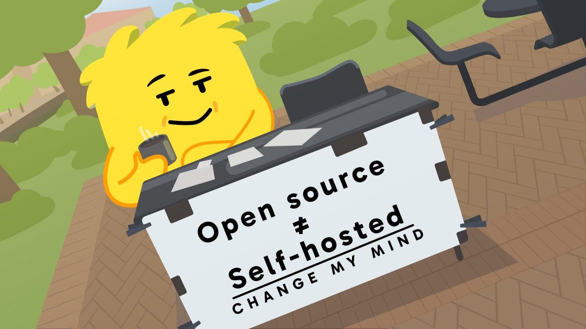 Bale at a folding table behind a sign that reads open source is not self-hosted, change my mind